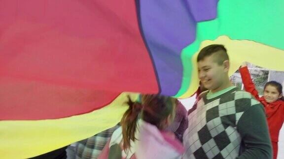 残疾儿童在多彩的降落伞下玩耍