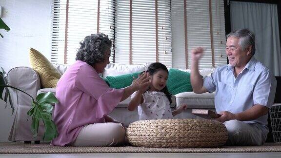 一对老人和孩子一起在家里的客厅玩拼图游戏白种人的家庭观念教育成长学习和发展的年龄4k决议