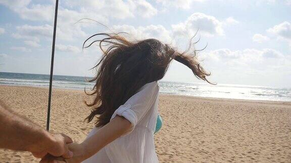 女孩牵着男人的手在热带异国的海滩上奔向大海跟着我拍的一个年轻女人拉着她的男朋友在海边暑假或假期的观点观点慢动作