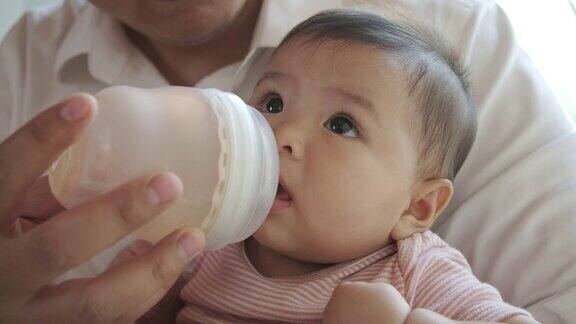 亚洲婴儿在白色的卧室里坐着爬着用奶瓶喂婴儿