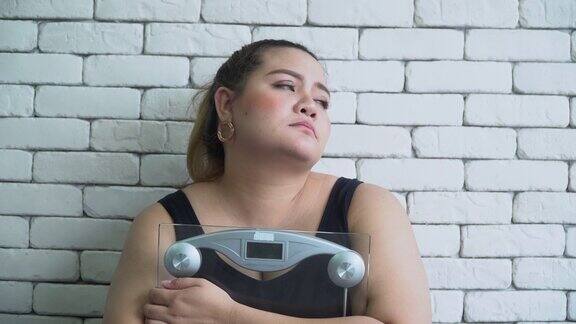 体型大的亚洲女人悲伤与体重秤