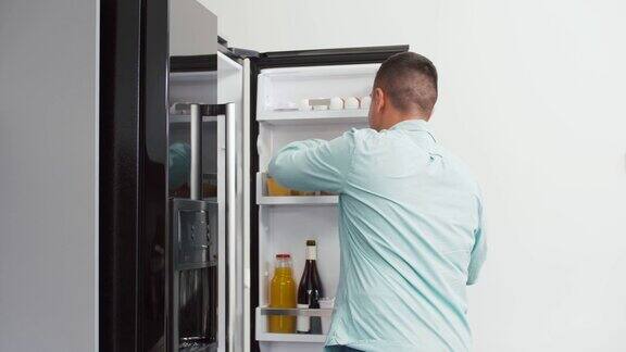 从家里厨房冰箱里拿苹果的男人