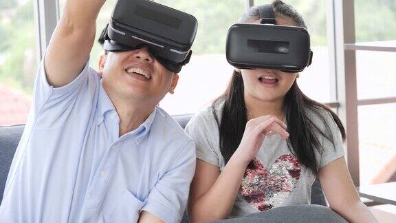 爸爸和女儿戴着虚拟现实眼镜一起玩电子游戏