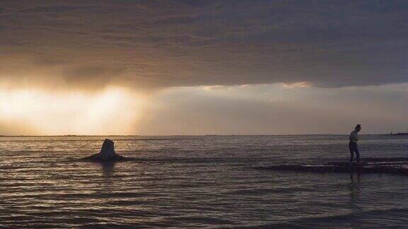 一位女性走在美丽日落的海岸上