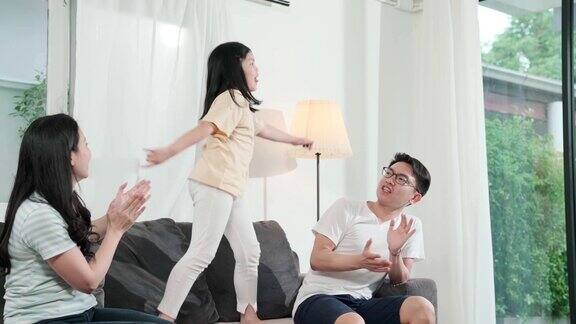 幸福亚洲妈妈爸爸女儿家庭享受舞蹈一起移动的乐趣和享受在沙发客厅的家庭背景亚洲家庭的理念