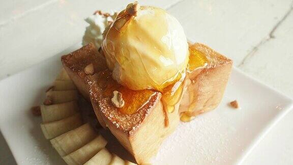 把金色的蜂蜜倒在烤面包上的冰淇淋上慢动作