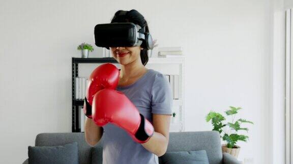 亚洲少女戴着虚拟现实眼镜和拳击手套在客厅里锻炼和玩虚拟游戏现代健身技术视频培训体育