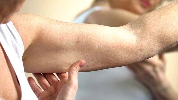 老年妇女看着手臂上的皮肤照顾自己衰老的变化