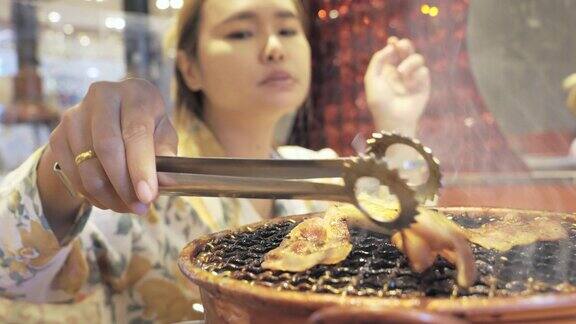 亚洲妇女在烤架上翻转美味的韩国烧烤猪肉