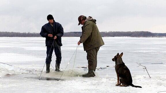 渔夫们在一个冰冻的池塘里把鱼从洞里拉出来冬季钓鱼