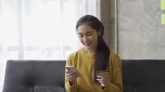 亚洲女性持有信用卡使用智能手机在线购物在家使用即时移动支付返现概念电子银行应用程序服务