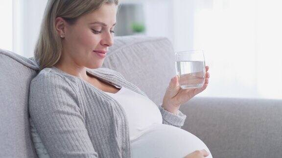 孕妇边喝水边抚摸肚子