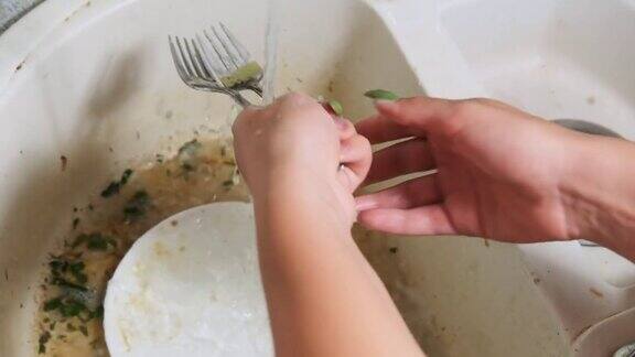 年轻女子在厨房的脏水槽里洗盘子慢动作
