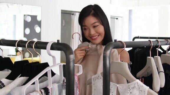 微笑的中国女人在精品店里买衣服
