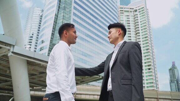 亚洲商人在高楼大厦的背景下握手合作协议谈判完成后即成功商业交易合并和收购概念