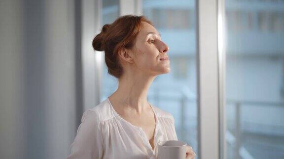 女商人在公司工作场所休息和喝咖啡而站在窗口