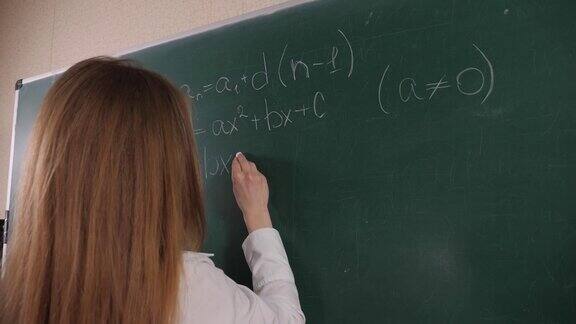 一个女学生在黑板上写数学公式的特写镜头