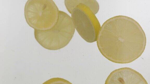 缓慢的运动新鲜的柠檬片落入水中溅起泡沫白色背景