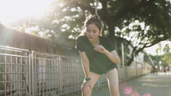 亚洲女运动员在城市的夕阳下进行有氧运动后精疲力竭地跑步休息