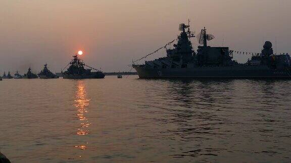 美丽的日落在海湾与战舰的剪影