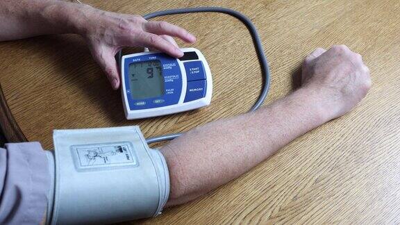 一名50多岁的男子用电子血压计测量自己肱动脉的血压