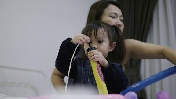 一个泰国的小女孩正在和她的妈妈和哥哥一起做一个气球同时用积极的情绪和放松的心情做一个气球气球形状的diy