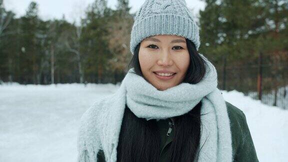 肖像美丽的亚洲女士穿着冬装站在户外公园微笑