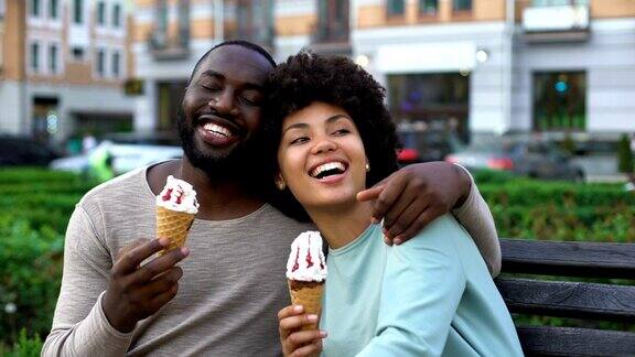 快乐的男朋友和女朋友在长椅上笑着浪漫的约会吃着冰淇淋