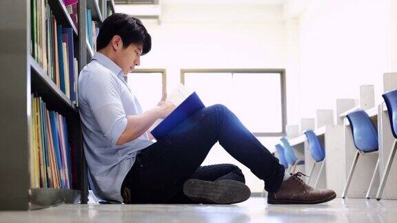亚洲男大学生在图书馆地板上看书做研究