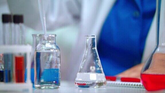 实验室医生用移液管将透明液体倒入实验瓶中