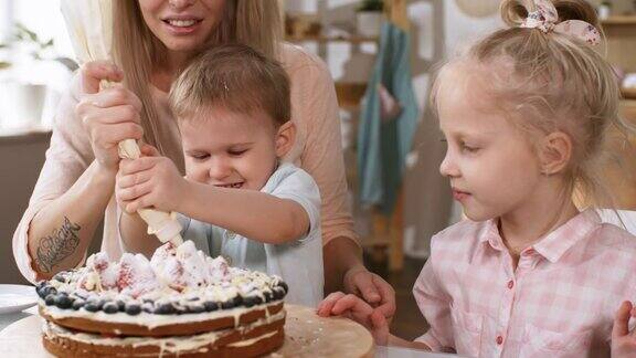 年轻的白人妈妈和孩子们装饰蛋糕