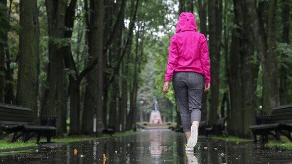 后视图视频的一个女人享受一个雨天在一个公园