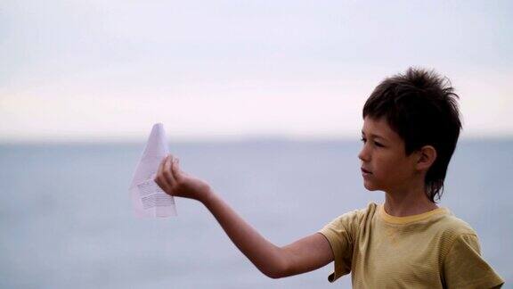 晚上热情的男孩在海边玩纸飞机