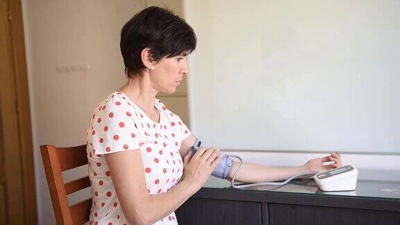 一名中年妇女用电子血压测量装置测量自己的血压
