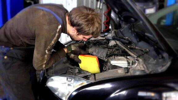 汽车修理工正在拆卸汽车发动机附近的肮脏空气过滤器