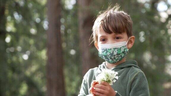 小男孩手持一束鲜花戴着防护口罩