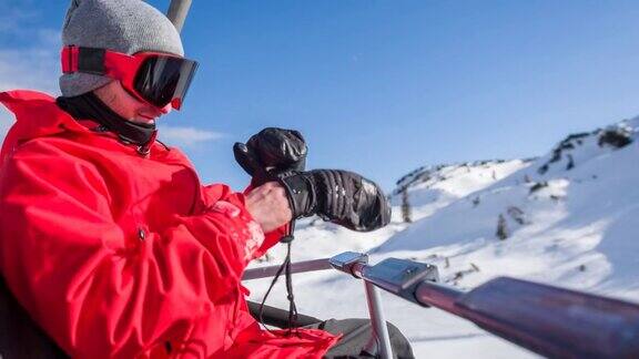 在一个阳光明媚的日子里滑雪者戴上他的手套乘坐滑雪缆车