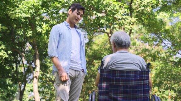 年轻的亚洲儿子在户外拜访年长的父亲并与之交谈