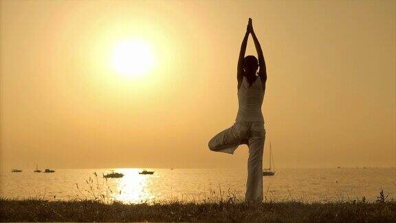 在海边落日下练习瑜伽的女人