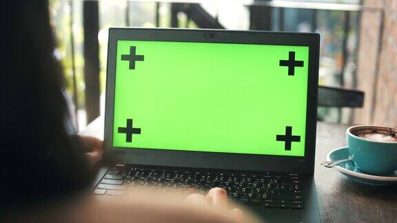 年轻的亚洲女子使用绿色屏幕的笔记本电脑