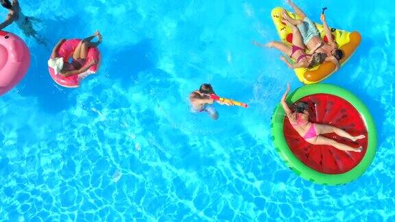 图片:微笑的年轻人在游泳池里的充气浮子上打水