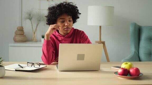 非裔美国女孩使用笔记本电脑在家庭办公室看屏幕打字聊天阅读写作电子邮件年轻女子正在进行虚拟会议在线聊天视频电话会议在家工作学习