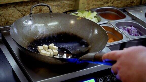厨师将油倒在热锅上然后加入豆腐