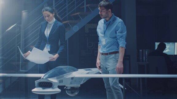 两名航空航天工程师正在研究无人机无人机原型航空科学家的谈话使用蓝图商用空中侦察机工业实验室