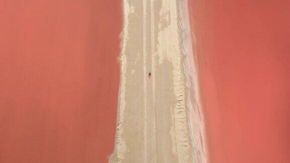 摄影:年轻的女性走在美丽的红色盐滩沙滩上