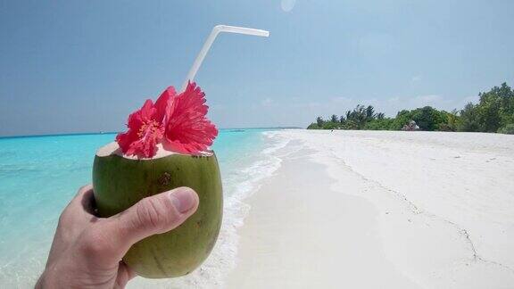 个人观点:马尔代夫阳光明媚的热带海滩上男人喝着椰子饮料
