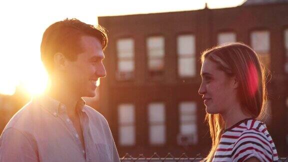 日落时分一对年轻的白人夫妇在布鲁克林的屋顶上聊天