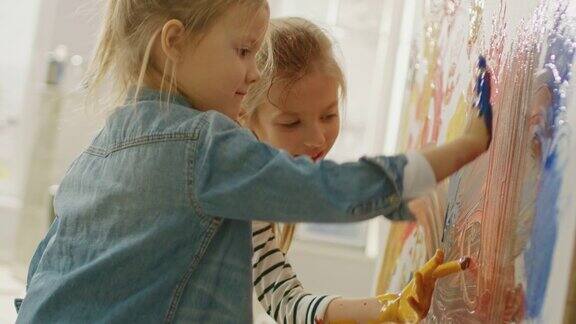 两个快乐的小女孩用彩色颜料蘸手在墙上画手印和抽象画他们开心地笑着房屋正在装修