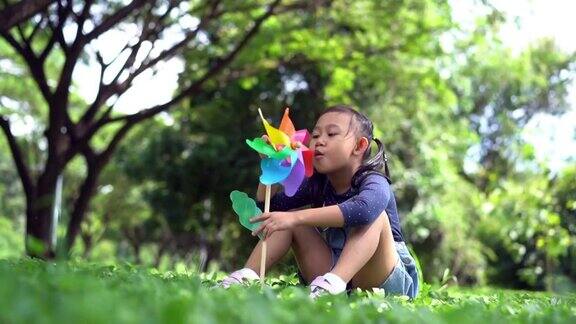 快乐的亚洲小女孩在花园里玩纸风车