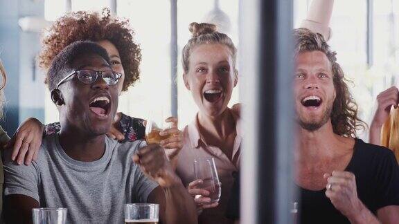 一群朋友喝啤酒在酒吧看体育赛事庆祝-慢镜头